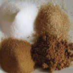 White Sugar, Evaporated Cane Juice, Brown Sugar & Demerrera Four piles of different types of sugar on a table: White Sugar, Evaporated Cane Juice, Brown Sugar & Demerrera.