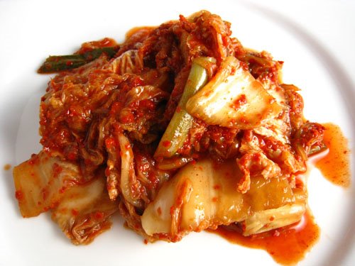 Red fermented and spicy Korean Kim Chi cabbage on a plate.