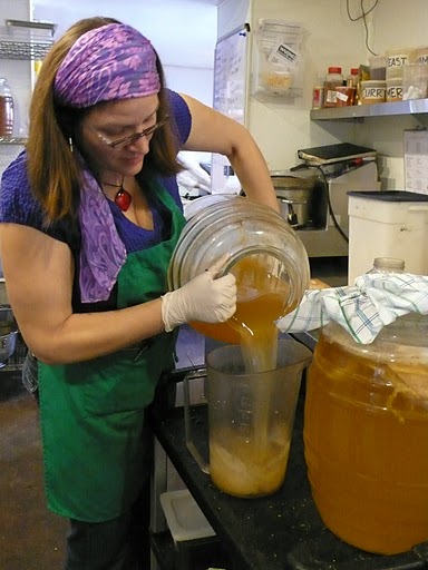 Hannah Crum, The Kombucha Mamma, pours a kombucha brew into a pitcher at Leaf Organics
