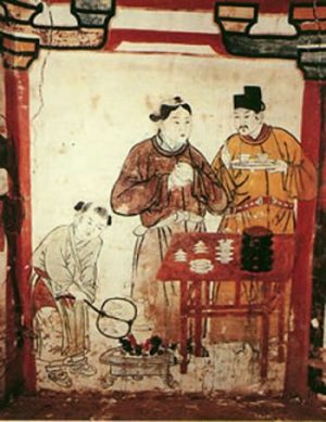 An old style Asian drawing of two men sampling tea while a woman or boy fans the fire.